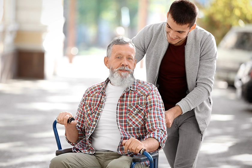 Young caregiver walking senior man outdoors