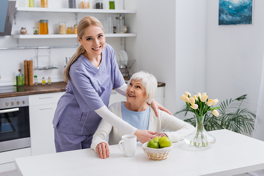 young nurse smiling camera while embracing happy aged woman