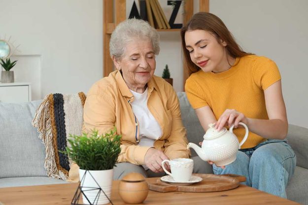 young woman pouring tea cup her grandmother home