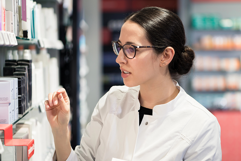 close portrait female pharmacist standing front pharmacy shelves