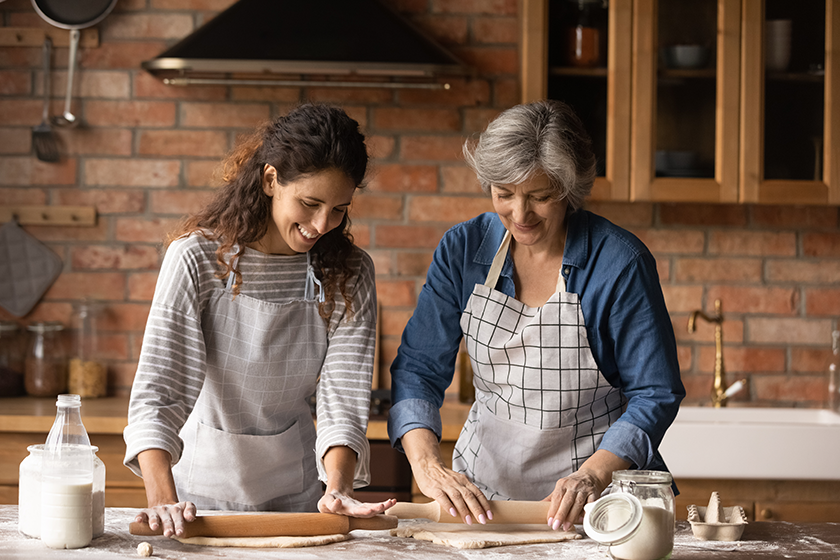 smiling latino mom and daughter bake in kitchen smiling latino mom and daughter bake in kitchen