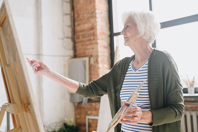 waist side view portrait white haired senior woman holding palette