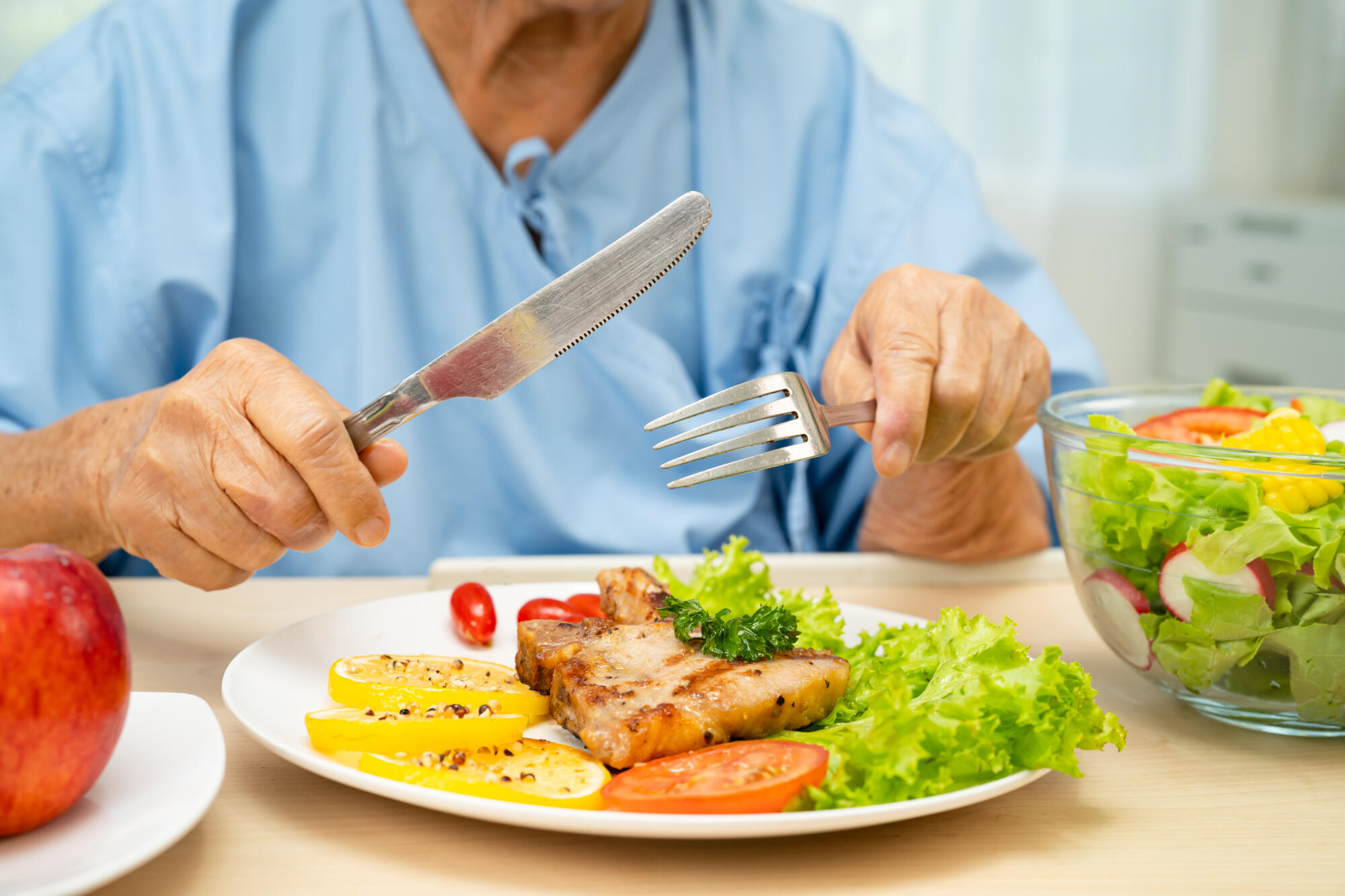 Asian elderly woman patient eating salmon stake and vegetable sa