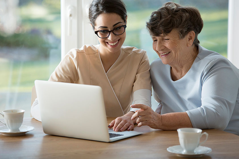 Smiling assistant teaching elderly woman