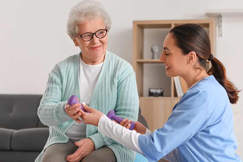 young caregiver senior woman training dumbbells