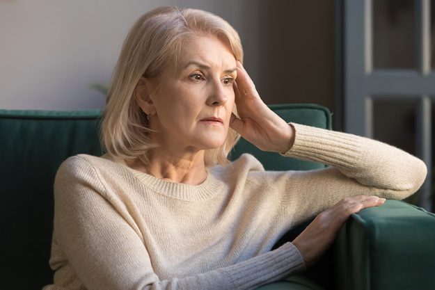Pensive middle aged lady looking away sit alone at home Pensive middle aged lady looking away sit alone at home