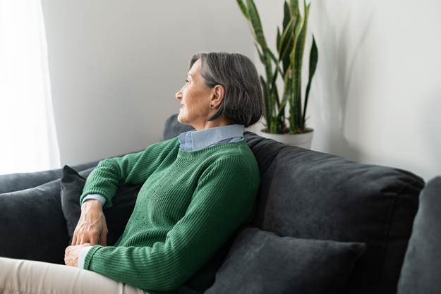 worried senior lady is looking in the window