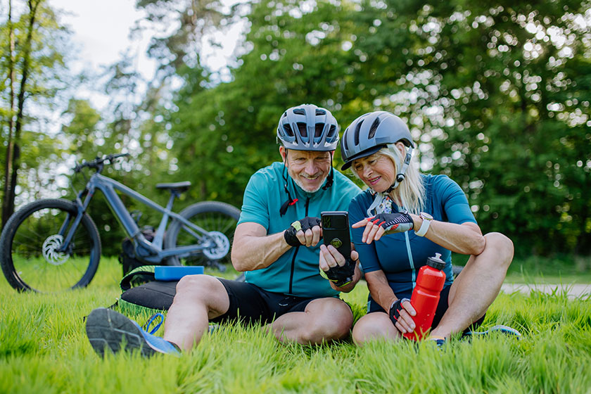 Active senior couple resting bicycle ride summer park sitting grass