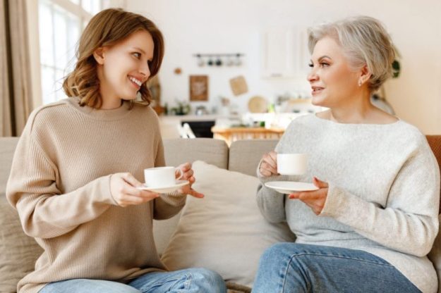 cheerful young woman middle aged mother drinking tea chatting friendly Cheerful young woman middle aged mother drinking tea chatting friendly