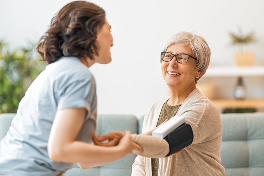 elderly patient caregiver measuring blood pressure