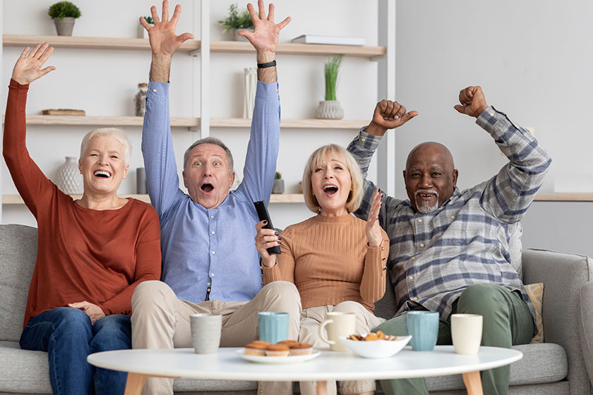Happy multiracial elderly people watching football game on tv