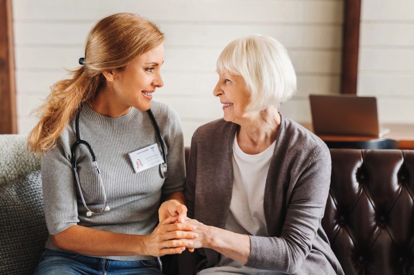 Pretty helpful carer doctor talking female patient home