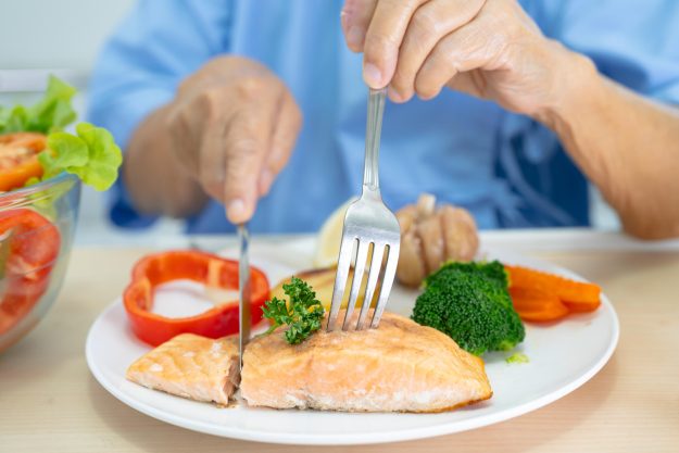 Asian senior woman patient eating Salmon steak breakfast with ve Asian senior woman patient eating Salmon steak breakfast with ve