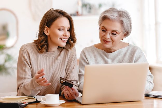 Senior woman credit card laptop smiling happy young granddaughter