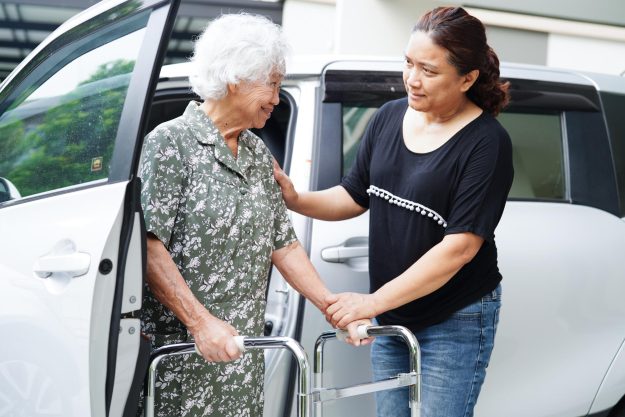Caregiver help Asian elderly woman disability patient get in her