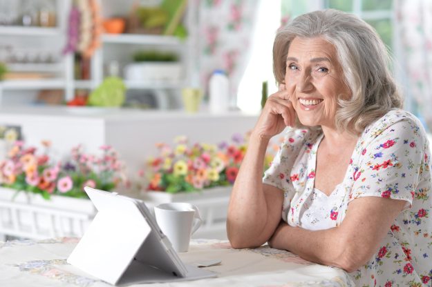 Portrait of beautiful senior woman using modern tablet while drinking tea Portrait of beautiful senior woman using modern tablet while drinking tea