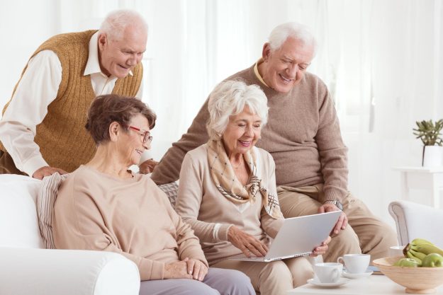 Two,Elderly,Couples,Excitedly,Looking,At,A,Laptop,In,A Two,Elderly,Couples,Excitedly,Looking,At,A,Laptop,In,A