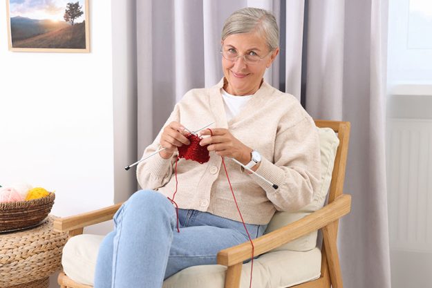 Beautiful senior woman knitting armchair home Beautiful senior woman knitting armchair home