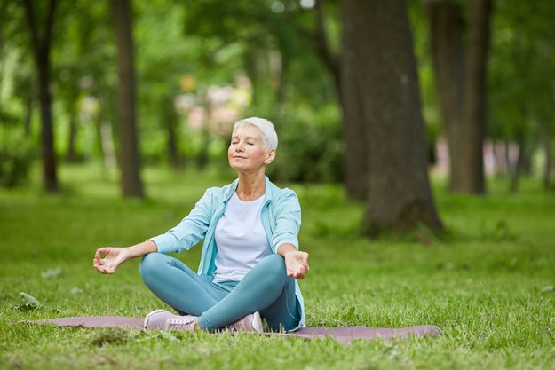 Beautiful senior woman spending summer morning time sitting mat park Beautiful senior woman spending summer morning time sitting mat park