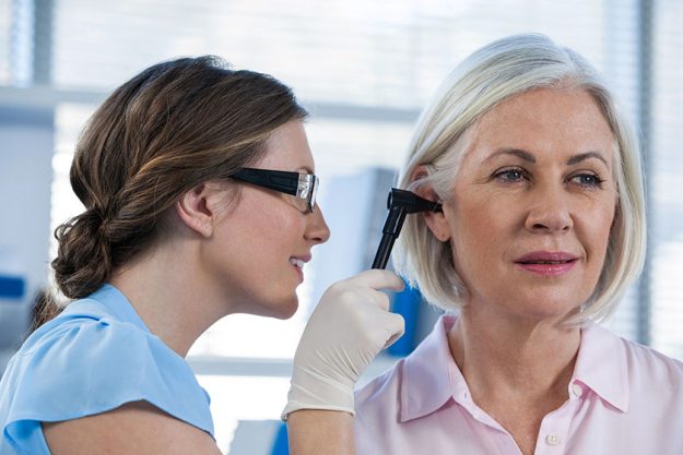 Doctor examining patients ear with otoscope Doctor examining patients ear with otoscope