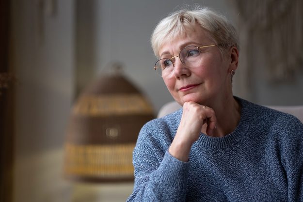 Grandmother looking in a window sitting at home alone dreaming Grandmother looking in a window sitting at home alone dreaming