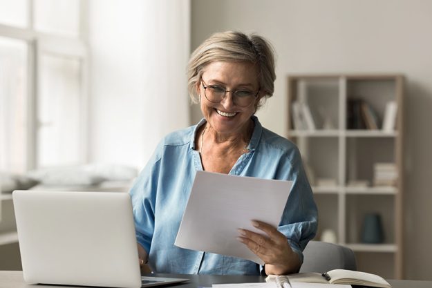 Mature woman read document confirms good news financial approval refund Mature woman read document confirms good news financial approval refund