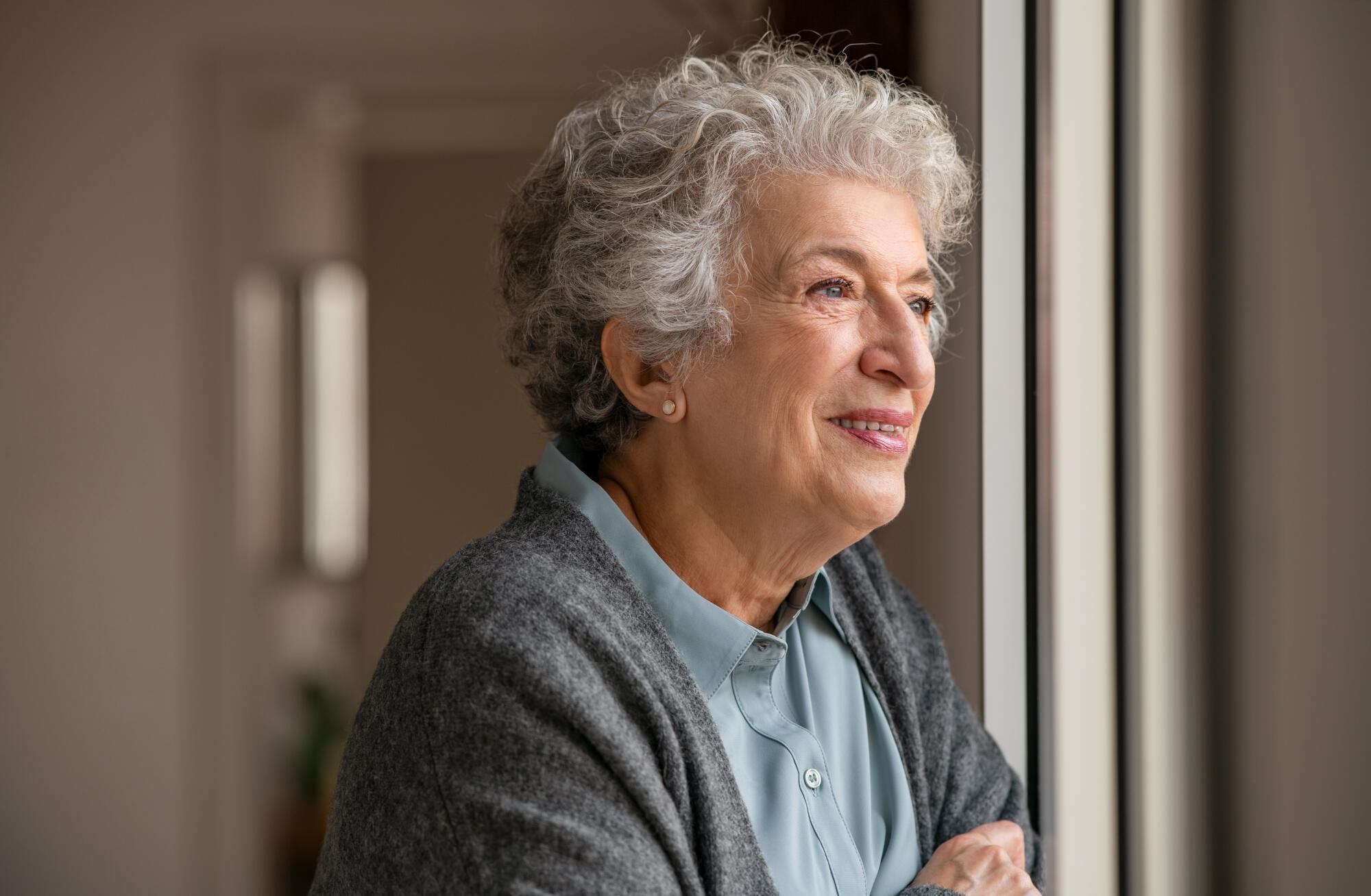 Smiling,Old,Woman,Looking,Through,The,Window.,Happy,Senior,Woman