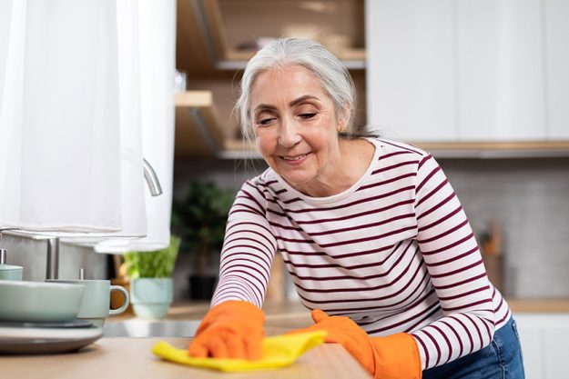 Portrait beautiful senior housewife washing table kitchen rag smiling elderly Portrait beautiful senior housewife washing table kitchen rag smiling elderly