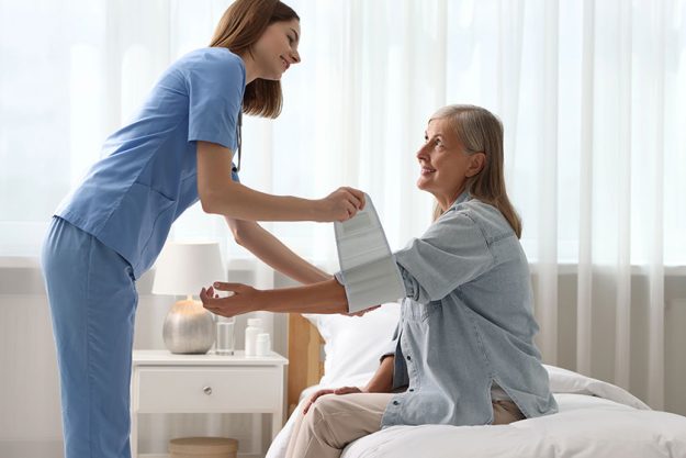 Smiling healthcare worker measuring patient blood pressure indoors Smiling healthcare worker measuring patient blood pressure indoors