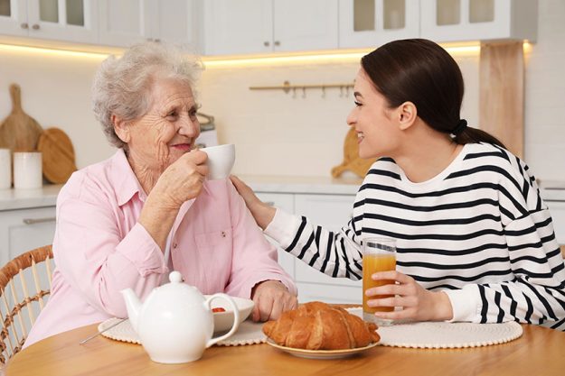 Young caregiver senior woman having breakfast table kitchen home care Young caregiver senior woman having breakfast table kitchen home care