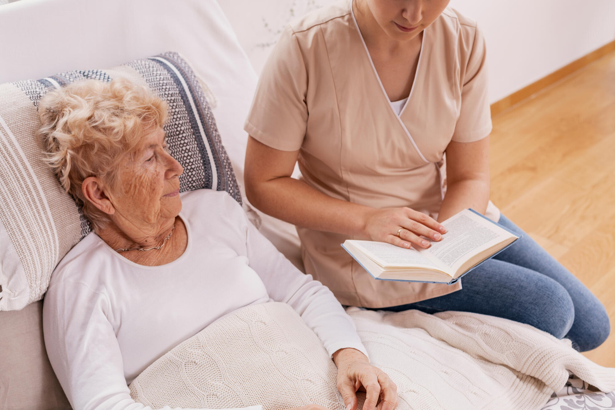 Helpful,Young,Carer,Reads,A,Book,To,An,Elderly,Woman