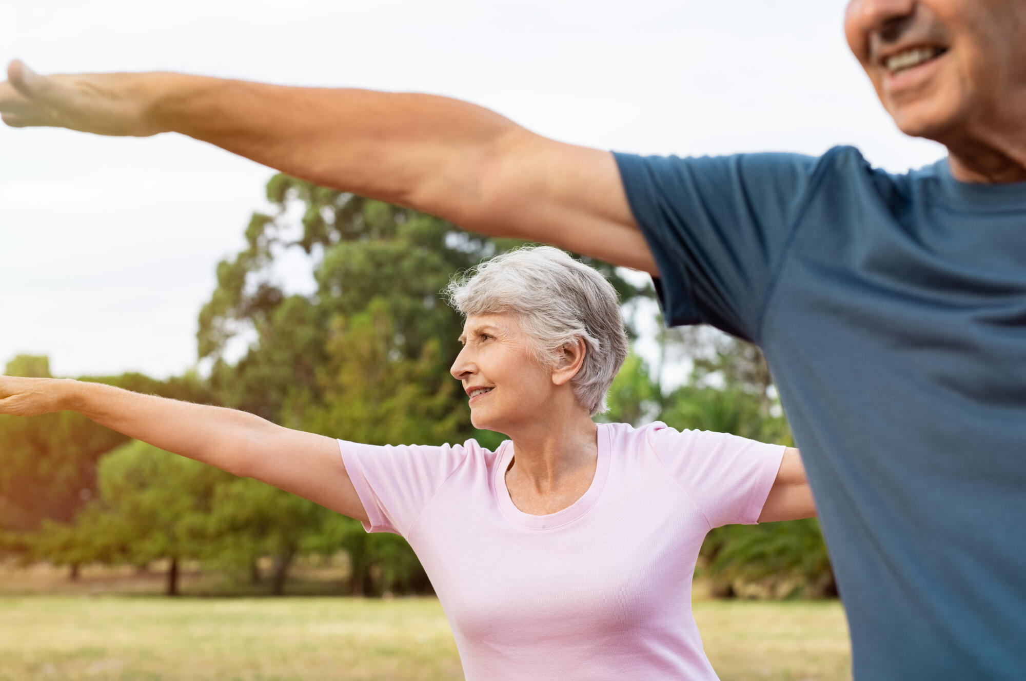 Senior,Woman,Stretching,Arms,At,Park,With,Her,Husband.,Happy Senior,Woman,Stretching,Arms,At,Park,With,Her,Husband.,Happy