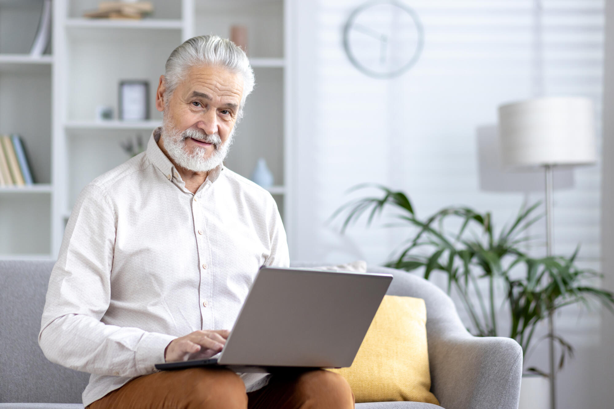 Senior man working on laptop in a bright living room