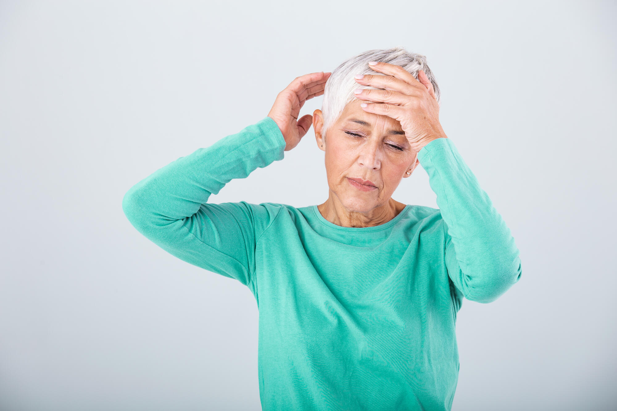 Attack of the monster migraine. Sinus pain. Unhappy Retired Senior Woman holding her head with pain expression . Face of senior woman suffering from headache Attack of the monster migraine. Sinus pain. Unhappy Retired Senior Woman holding her head with pain expression . Face of senior woman suffering from headache