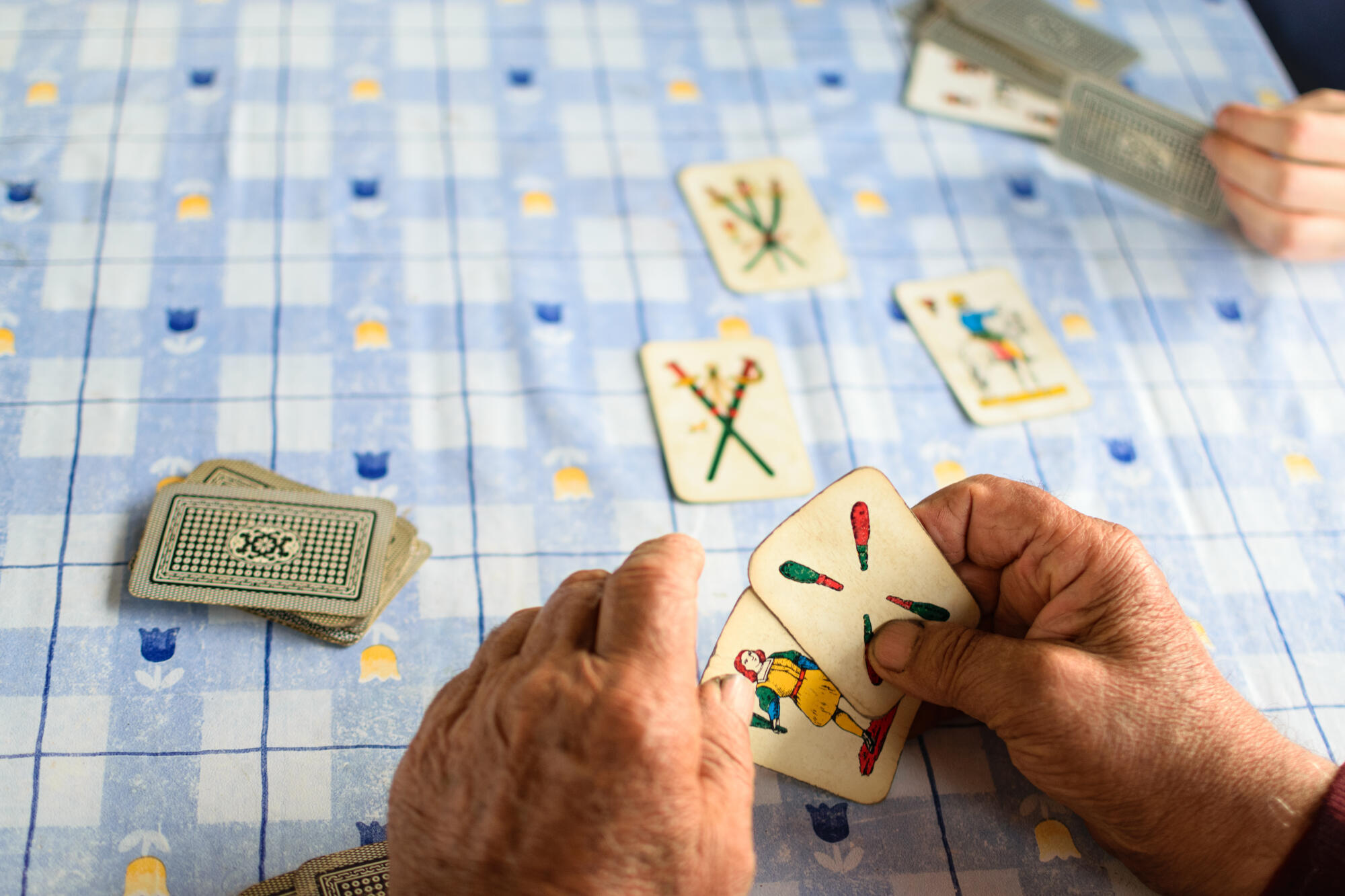 Elder hands playing cards on a blue table
