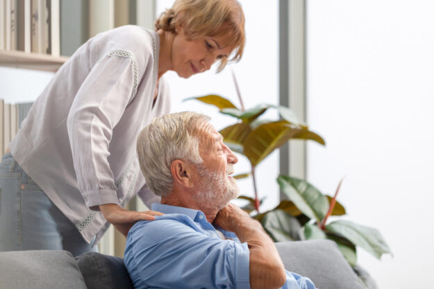 Senior couple in living room, Elderly man with pain in the shoul