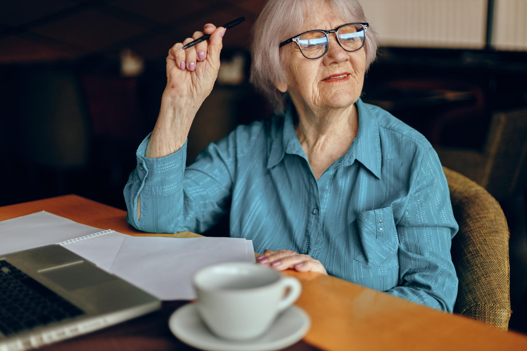 Happy senior woman sitting in a cafe with a cup of coffee and a laptop Lifestyle unaltered Happy senior woman sitting in a cafe with a cup of coffee and a laptop Lifestyle unaltered