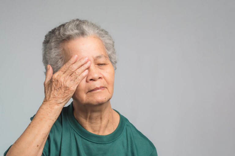 Portrait of a senior woman with eye pain while standing on a gra Portrait of a senior woman with eye pain while standing on a gra