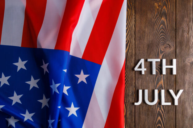 the words 4th july and crumpled usa flag on flat textured wooden surface background