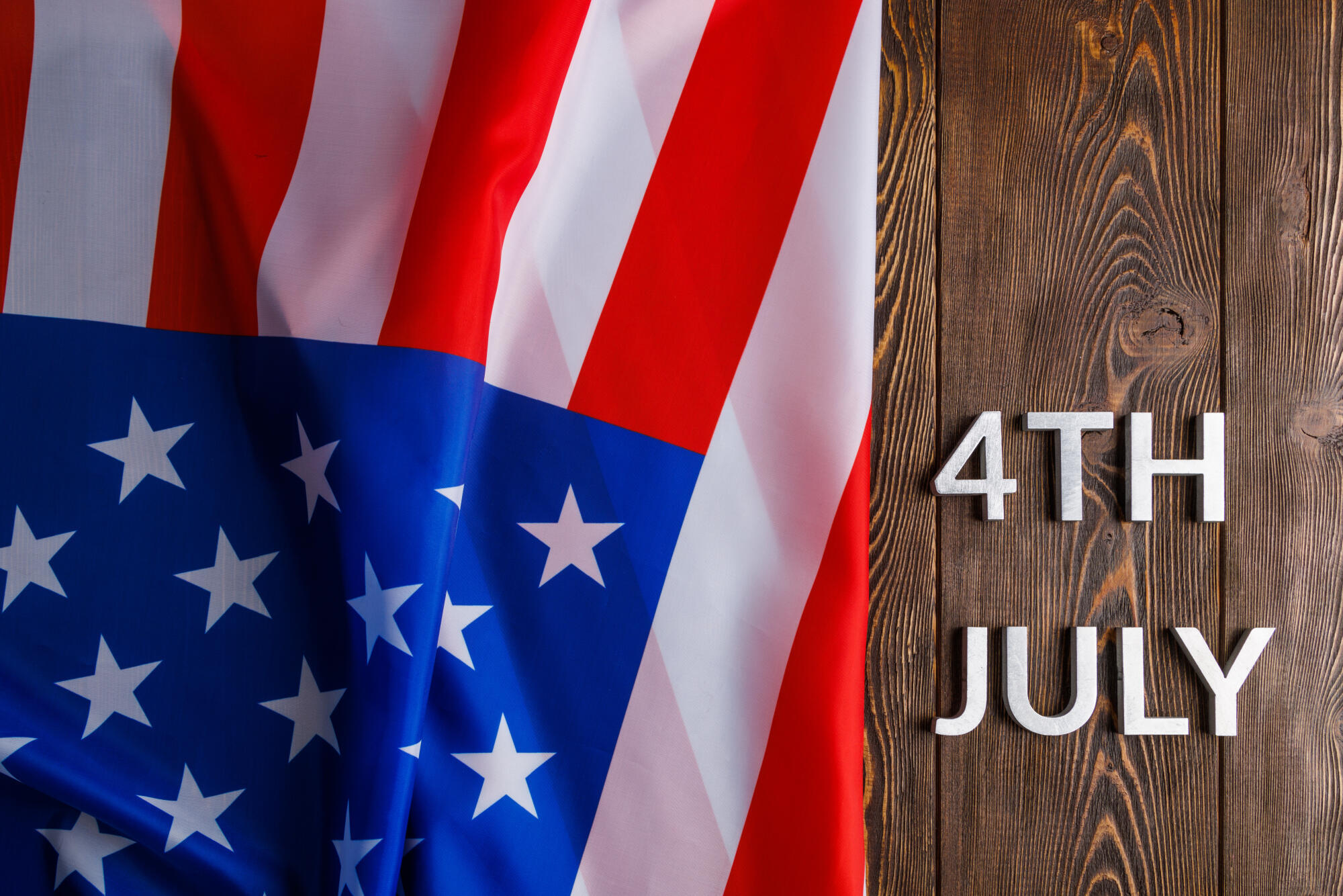 the words 4th july and crumpled usa flag on flat textured wooden surface background the words 4th july and crumpled usa flag on flat textured wooden surface background