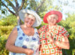 Walk in the garden. Two retired women best friends in hats walk happily in the garden.