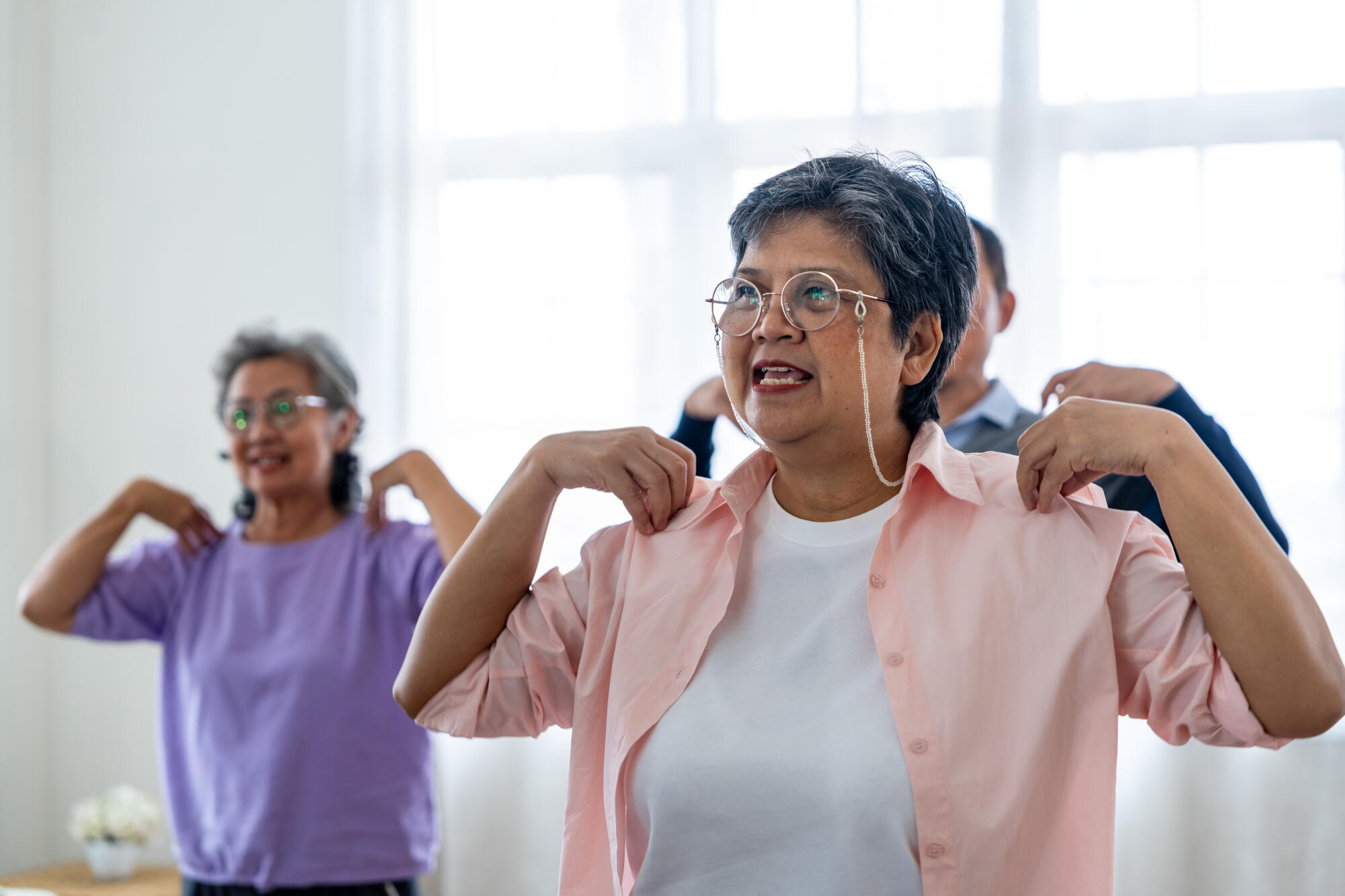 Portrait of elderly smiling Asian woman and people aerobics in n