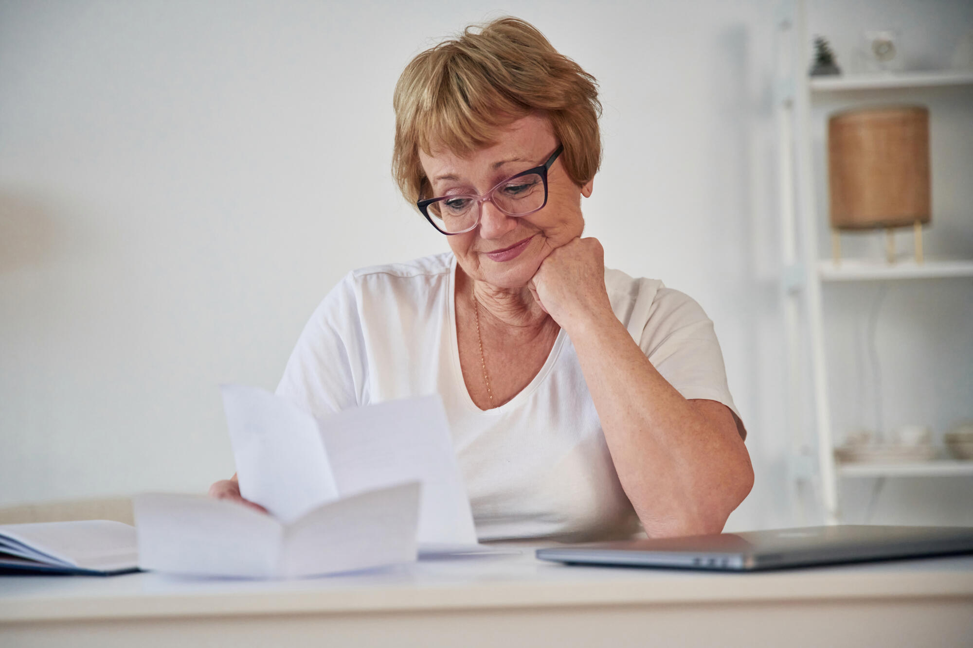 Reading the information from paper. Senior elderly woman is at home in the living room