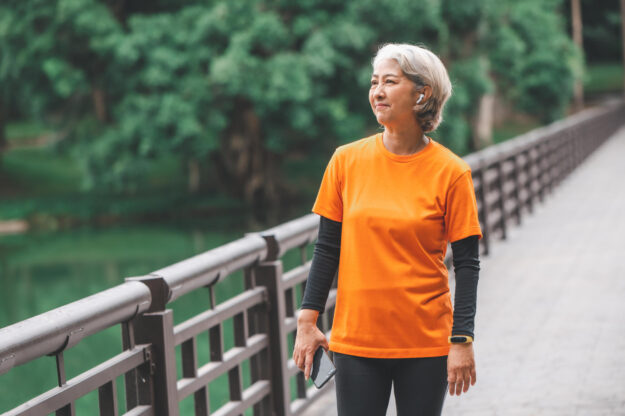 white haired elderly person exercising in the park early in the