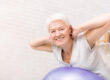 Happy mature woman doing exercises with fitness ball