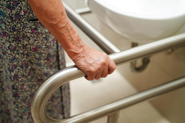 Asian elderly old woman patient use toilet support rail in bathr Asian elderly old woman patient use toilet support rail in bathr