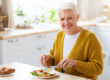 Cheerful healthy senior woman enjoying her lunch at home