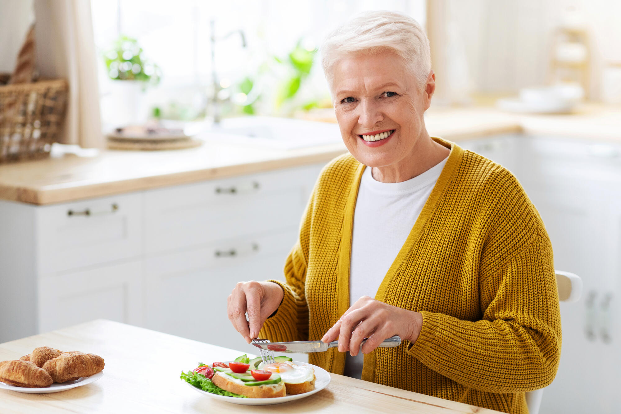 Cheerful healthy senior woman enjoying her lunch at home Cheerful healthy senior woman enjoying her lunch at home