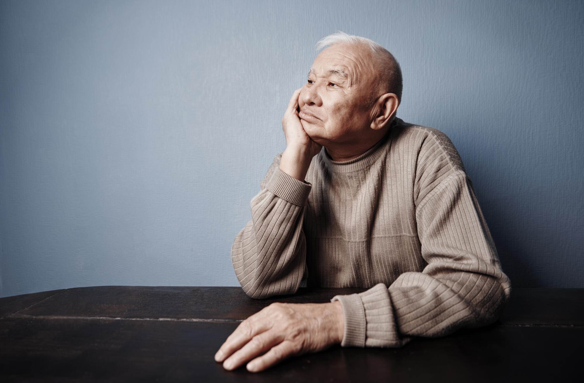 Pensive and thoughtful senior man sitting at the table Pensive and thoughtful senior man sitting at the table