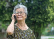Happy beautiful senior woman is using a smartphone and looking u